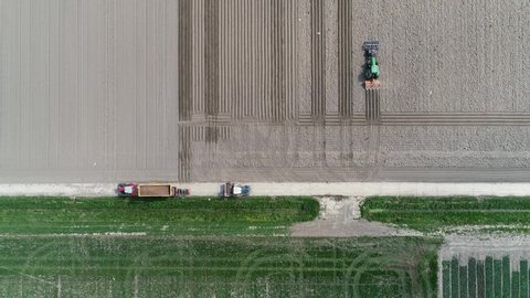 Aerial top down view of farmers working together showing several agricultural machines tractors with implements and one farmer adding materials to the load in a tractor 4k high resolution quality