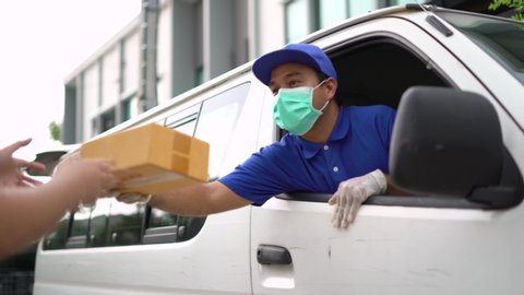 Corona Virus Concept. Asian blue delivery man wearing protection mask and medical rubber gloves send a package to customer on the cargo van. 4k resolution and slow motion shot.