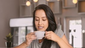Medium 4k video of a young, beautiful, Latin Hispanic woman drinking coffee in cafe. 