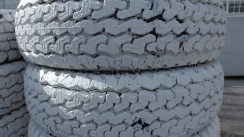 Pan shot of selective focus of stack of white painted used old car tires in a factory of auto tire repair lying on floor 