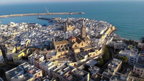 Aerial shot of a beautiful italian city by the sea. Drone flight over old town of Monopoli. View of the sea, houses and churches. Bari, Puglia, Italy. 4K