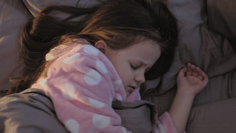 Child insomnia. Sleep disorder. Young girl tossing turning in bed disturbed with nightmare.