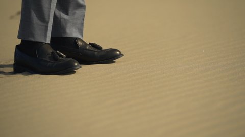 a figure beside the footprints of a person walking through the desert.