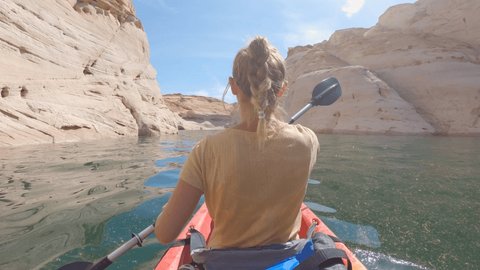 Rear view of young woman canoeing inside canyon in Western USA. Woman canoeing on the Colorado river.
