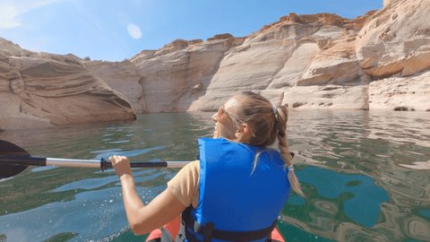 Rear view of young woman canoeing inside canyon in Western USA. Woman canoeing on the Colorado river.