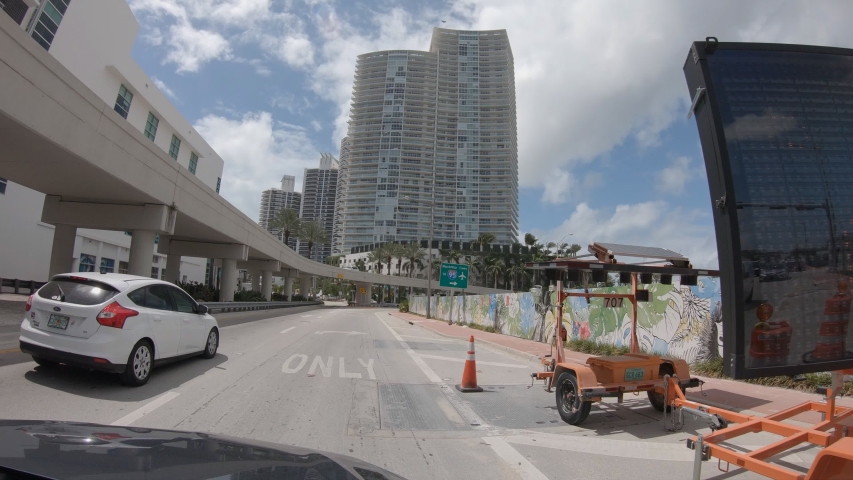 Time lapse shot mounted on car, vehicle drives along downtown Miami, Florida USA. POV vehicle driving in Miami  Royalty-Free Stock Footage #1052116720