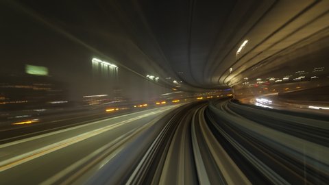 Modern automated metro line of Tokyo, cabin view timelapse at night, car make round turn and pass bridge. Accelerated shot with fine front perspective, outdoors seen in motion blur