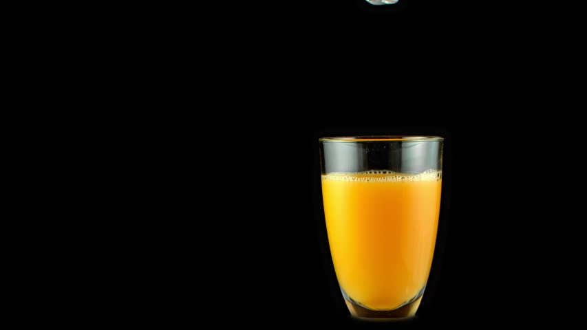 Super Slow Motion Shot of Ice Cubes Falling into Glass of Orange Juice and Making Splash at 1000 fps. Royalty-Free Stock Footage #1052127613