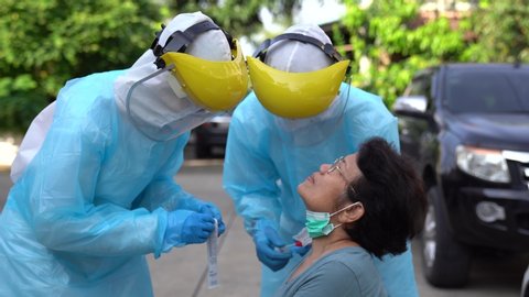 Doctors in protective clothing performed a nasal / mouth swab congestion. From the patient to test for coronavirus covid-19 infection.