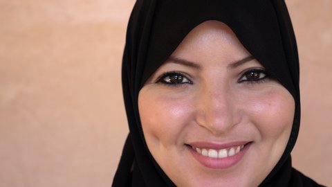 Portrait of a beautiful Moroccan Arab Muslim woman with traditional black hijabniqab, smiling, looking into the camera. Confident and happy. Real-time footage.