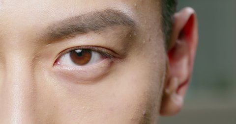 slow motion of male eye close up from asian young man half face