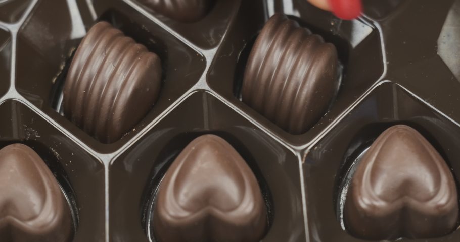 Box of chocolate bonbon candies put on a table and hands taking... chocolate bonbon candies put on a table and hands taking... 