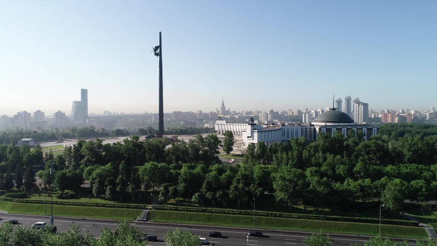 Aerial view of the Victory Park on Poklonnaya Hill, surrounded by green trees. City buildings on the background at early morning. Taken by drone at Moscow