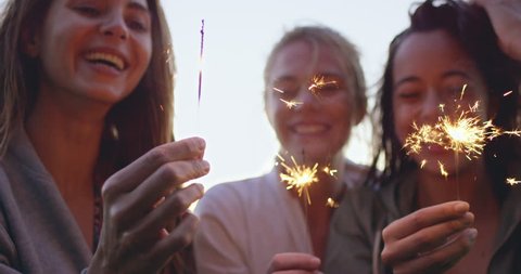 close up shot of teenage girls with sparklers celebrate and laugh