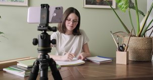 Teenager girl studying online using smartphone, listening and talking at video conference. Distance learning, e-learning, technology, education, teens concept. Slider tracking shot.