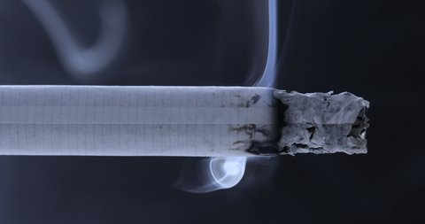 Smoldering cigarette on a black background. Smoke from a cigarette	
