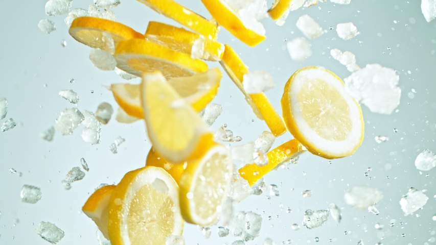 Super Slow Motion Shot of Flying Fresh Lemon Slices and Crushed Ice on Blue Background at 1000 fps.