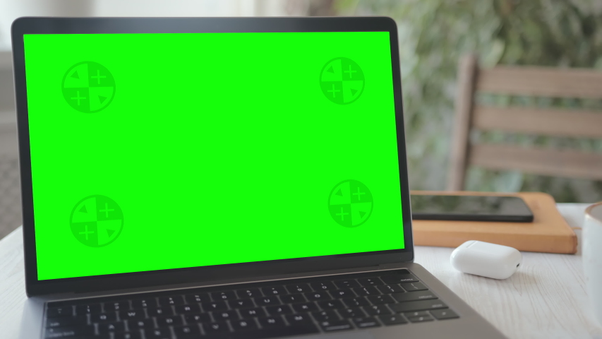 Mock-up Laptop Computer with Chroma Key Green Screen Set on Working Space in Home Office. A Cup of Hot Coffee and a Croissant Placed near the Computer. Concept of Working from Home. Zoom out Shot. Royalty-Free Stock Footage #1052170720