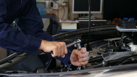 male mechanic using wrench to repair the engine, car service