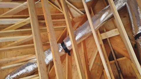 House under construction of install of HVAC vent in roof of wooden beams