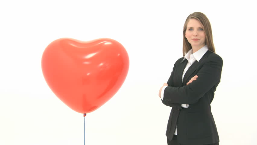 Woman standing next to heart balloon and crosses her arms