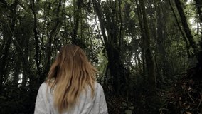 Rear view of young woman walking in tropical rainforest exploring nature and enjoying national park. People travel exotic destination