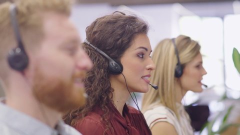 Portrait of confident woman working in a call center while looking at camera. Customer care rappresentative working in modern office sitting in a row. Support online with latin call center agent.