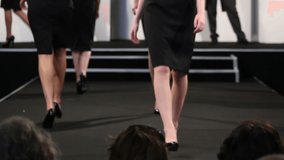 Female Models walking on a Catwalk / Runway at a Fashion Show. High Heels and black dresses. Stock Video Clip Footage