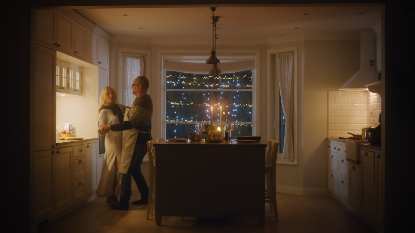Happy Senior Couple in Love Have Romantic Evening, Dancing in the Kitchen, Celebrating Anniversary. Elderly Lovely Husband and Wife Have Romantic Evening with Wine, in Stylish Cozy Kitchen Interior | Shutterstock HD Video #1052181889