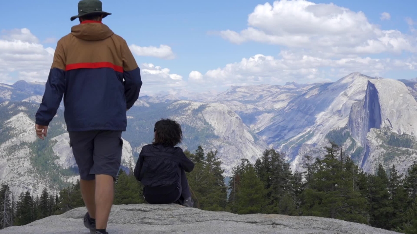 A couple looking at the park and waterfalls from Glacier point in Yosemite National Park. California, United States
