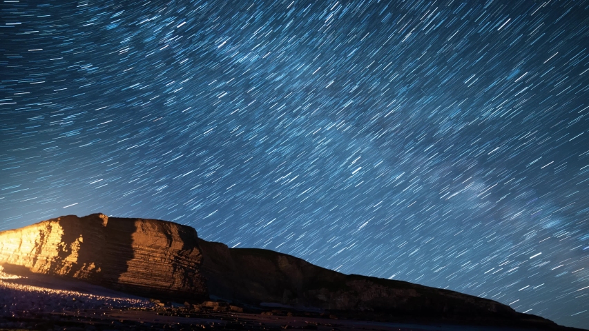 Star trails over light painted cliff in Dunraven Bay, South Wales