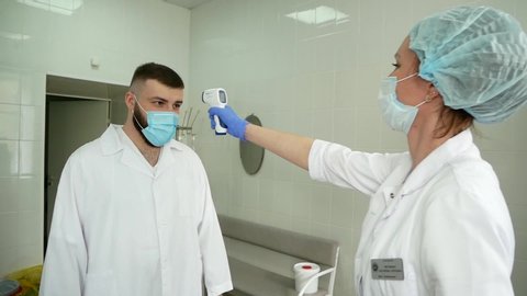 Chelyabinsk, Chelyabinsk region \ Russia - 29.04.2020: In coronavirus pandemic. The doctor measures temperature and conducts initial check for coronavirus .