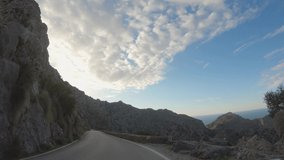 4K POV slow motion footage of driving through beautiful rocky mountain landscape with Mediterranean sea on horizon. Scenic shot during sunset. Winding road. Mallorca, Spain. Epic Point of view video