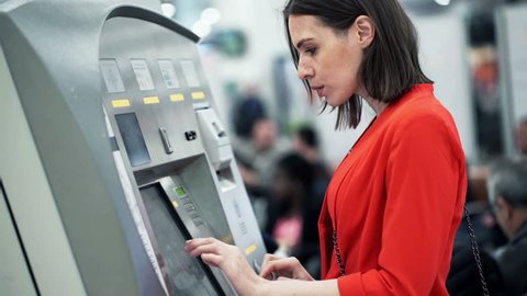 Young woman buying ticket from vending machine at station
