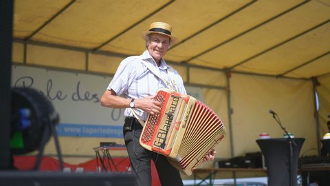 VILDE LA MARINE, FRANCE - 7TH JULY 2019: Local man playing harmonium at festival of the mussels in the Vilde La Marine, near of the Cancale, France, Europe.