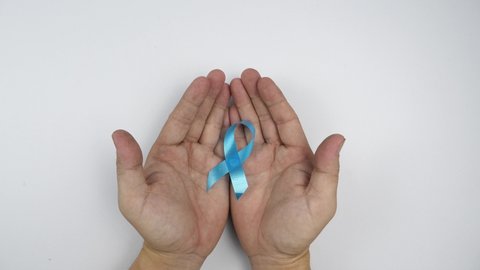 Hold hands sky blue colo ribbon on white background.
National Child Abuse Prevention Month, 
Men with localised prostate cancer are risk stratified 
top view.  
