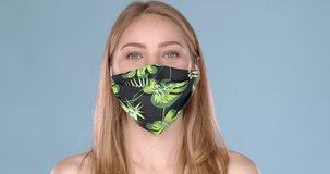 Adorable young girl taking off her face mask against viruses with huge relief. Taking big breath and smiling. Slow motion video. Studio portrait.