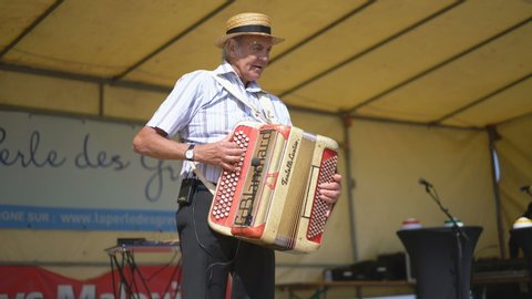 VILDE LA MARINE, FRANCE - 7TH JULY 2019: Local man playing harmonium at festival of the mussels in the Vilde La Marine, near of the Cancale, France, Europe.
