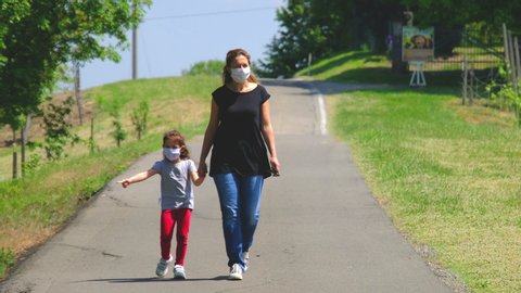 mother and daughter family with mask walk on deserted empty country road after covid 19 coronavirus outbreak .