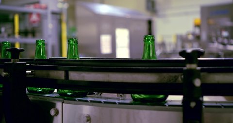 conveyor belt. glass green empty bottles move along it. close up. side view