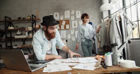 A hipster tailor couple is working together at their office, designing their new fashionable clothes collection - small family business concept 4k footage วิดีโอสต็อก