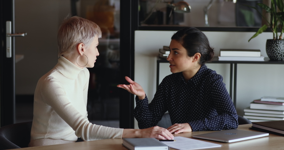 Professional indian saleswoman, insurance broker having business conversation negotiating with client, convincing caucasian business woman customer to buy insurance services. Mentoring, apprentice Royalty-Free Stock Footage #1052221222