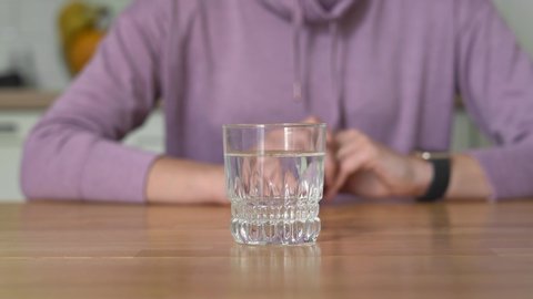 Young woman at home drinks water and wants to eat. Intermittent fasting concept