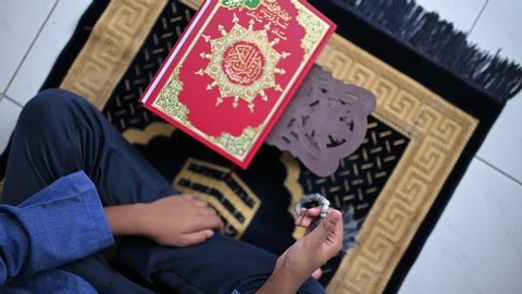 An islamic concept for Ramadhan. Qoran, Dates and a tasbih (rosary beads) on top of a sajadah (praying mattress), selectiv focus with Panning shot, On 4k Footage.