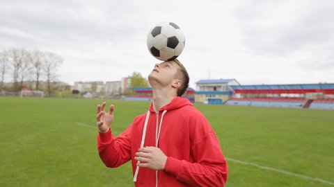 Young football player doing juggling with his head