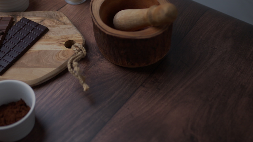Chocolate cake ingredients: Malted Milk biscuits, a bowl of Cacao, a glass of Buttermilk, a piece of Butter, a bunch of milk and dark Chocolate on the wooden dark table.