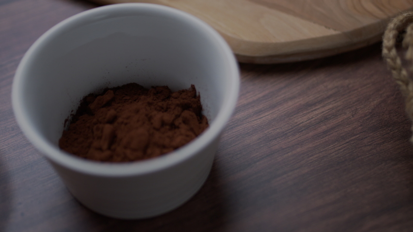Chocolate cake ingredients: Malted Milk biscuits, a bowl of Cacao, a glass of Buttermilk, a piece of Butter, a bunch of milk and dark Chocolate on the wooden dark table.