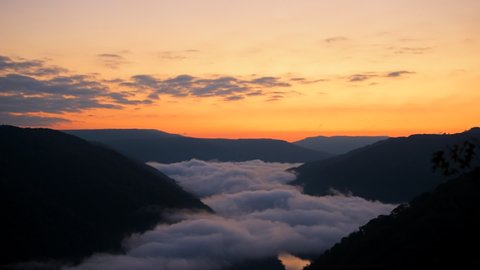 Seamless loop cinemagraph of mountains fog mist clouds moving morning above new river gorge valley in Grandview Overlook, West Virginia during colorful sunrise