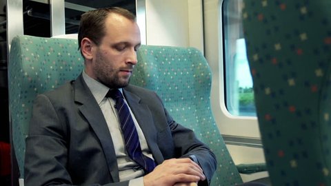 Young businessman checking time on smartwatch sitting in train
