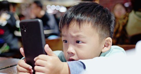 Asian boy watch program on cellular very intently without a move